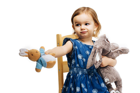 toddler girl sharing and offering a plush toy rabbit