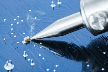 Electronic manufacturing and repair concept - soldering iron in a process of fixing microcircuit