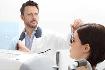 optometrist examining eyesight, woman patient pointing at the hole on plexiglass, isolated on white, ocular dominance test - obrazy, fototapety, plakaty