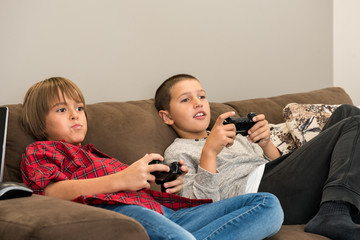 Two happy  young boy friends playing video games, holding remote controlers