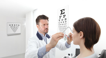 optometrist with trial frame examining eyesight  woman patient in optician office