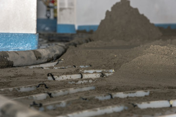 Screed flooring is processed in a residential building. Sand and cement mixture is introduced over floor heating. Sand and cement floor screed. Concept: construction site and craft