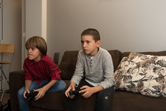 Two happy  young boy friends playing video games, holding remote controlers