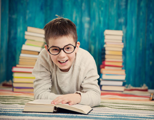 eight years old child reading a book at home. Boy studying at table on blue background