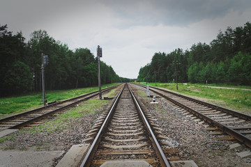 Obraz premium Rusty railroad with rocks in the forest under light blue cloudy sky. Old railroad in poor country.