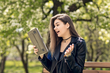 Beautiful caucasian girl student sitting on bench in park reading book