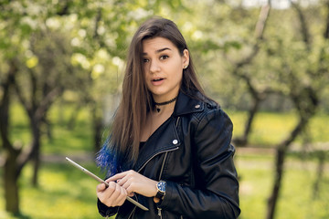Beautiful caucasian girl in black leather jacket. Young woman holding a tablet
