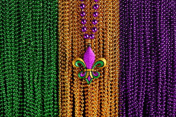 Green, gold, and purple Mardi Gras beads with Fleur de lis background - obrazy, fototapety, plakaty