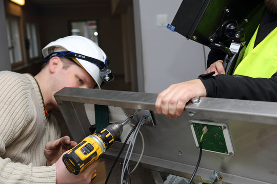 Elektrycy wkręcają śrubę w maszynie.