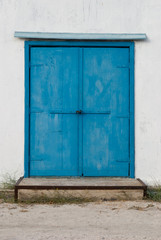 Old vintage blue metal door in a white wall, concrete foundation step, bolt lock, visor