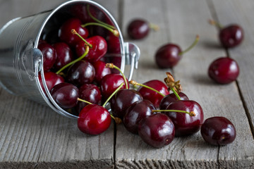 Ripe cherries and bucket on old wooden table