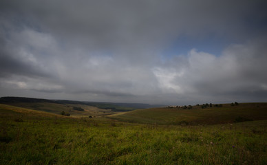Obraz premium Storm clouds over the sloping meadows in the mountains.