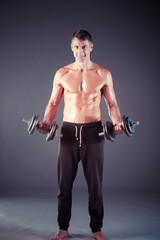 Fototapeta na wymiar Handsome muscular man working out with dumbbells. Personal fitness instructor. Personal training.