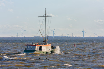 Dutch fishing ship at lake ijsselmeer with wind turbines at the horizon © Kruwt