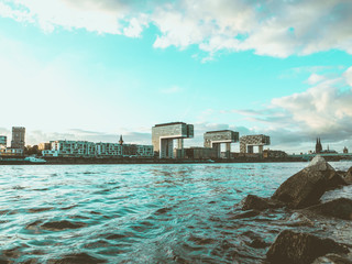Iconic Crane Houses in Cologne, Germany, with River Rhine and Rocks in Foreground