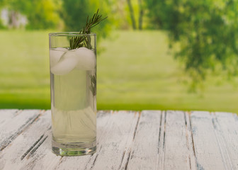 Lemonade on a white wooden table with rosemary sprig