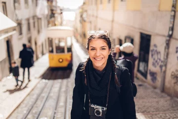 Foto op Plexiglas Young cheerful woman walking down the street of Lisbon.Amazed tourist visiting Europe off season during winter.Student in Portugal,Europe on a spring brake trip exploring big cities.Positive female © eldarnurkovic