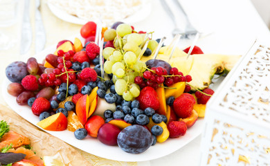 Delicious fruits on plate on table close-up