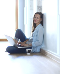 Young beautiful woman at home sitting on the floor with laptop. Young beautiful woman.