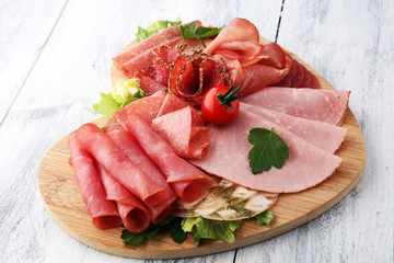 Food tray with delicious salami, pieces of sliced ham, sausage, tomatoes, salad and vegetable - Meat platter with selection