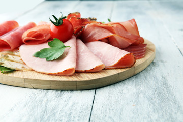 Food tray with delicious salami, pieces of sliced ham, sausage, tomatoes, salad and vegetable - Meat platter with selection