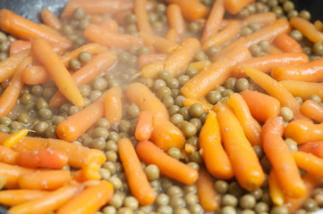 détail petit pois carottes dans une poêle 