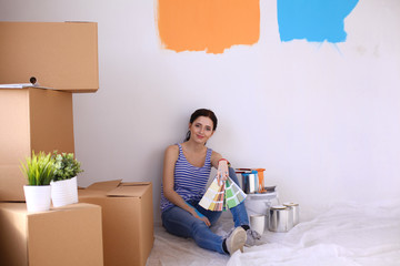 Woman choosing paint colour from swatch for new home sitting on wooden floor. Woman in the house