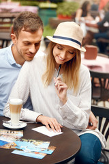 Travel. Beautiful Couple Writing Postcards Sitting At Cafe Table