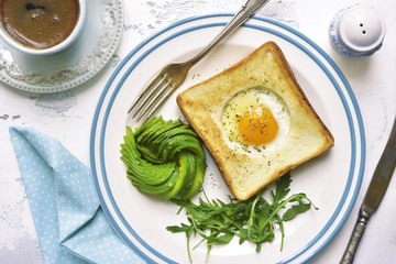 Fried toast with egg filling,avocado rose and arugula leaves with cup of coffee - healthy breakfast concept.Top view.