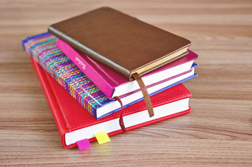several colored notebooks on a wooden table, top view