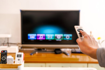 a women hand hold the remote control of the TV box in the living room, the black screen TV the TV box in the living room