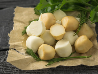 Freshly prepared smoked and regular mozzarella cheese in paper on a wooden table.