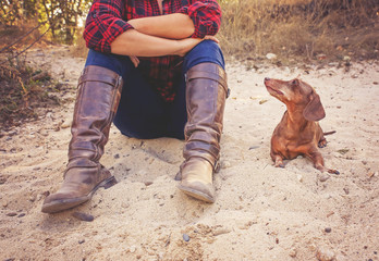 authentic candid photo of a cute senior dachshund with his owner wearing brown leather boots and...