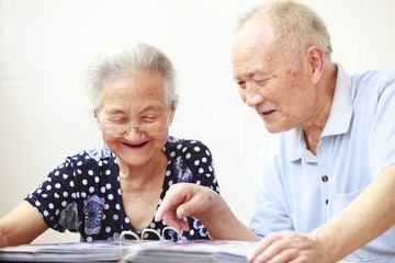 senior asian couple reading in home