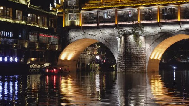 Boat sailing along the Tuojiang River in Fenghuang at night