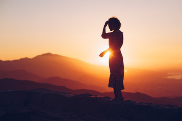 Woman Silhouetted Against Sunset on Mountains