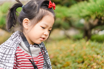 Cute little asian girl takes picture with mirrorless camera in winter in Japan garden.