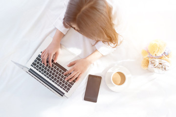 Portrait of a young business woman ,laptop,cup of coffee. Business concept a laptop drinking coffee with her computer on the bed