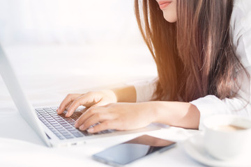 Fototapeta premium Portrait of a young business woman ,laptop,cup of coffee. Business concept a laptop drinking coffee with her computer on the bed