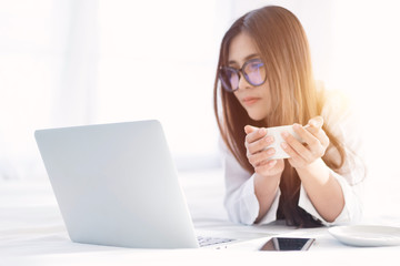 Portrait of a young business woman ,laptop,cup of coffee. Business concept a laptop drinking coffee with her computer on the bed