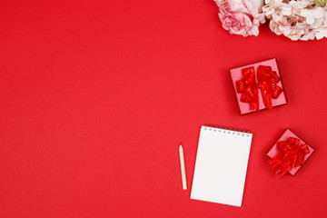 Red gift box with notebook on red background with copy space. Close up. Top view. Happy new year. Valentines day background.