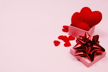 Valentines day background. Feminine desk workspace with gift box and red heart on pink background...