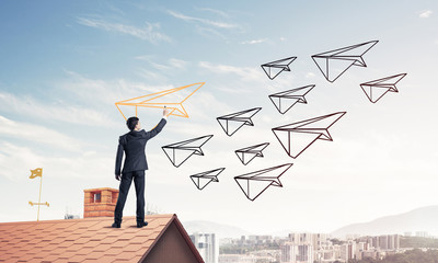 Businessman standing with back on house brick roof and drawing. 