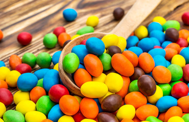 Wooden spoon with colorful round candies on the table.
