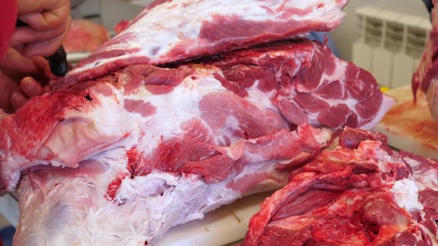 Butcher cutting pork meat on the table.
