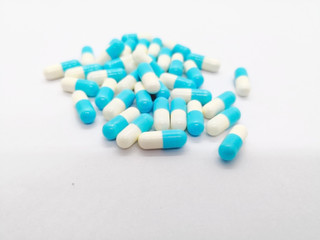 Medication concept. Indomethacin is generic name of drug, use for relief pain and reduce muscle inflammation. Many white-blue capsules isolated on white background, focus on foreground and copy space.