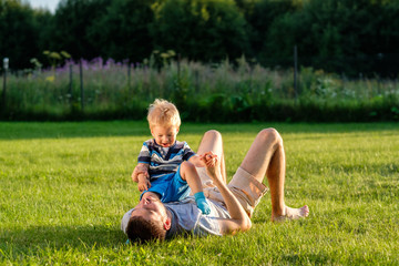 Naklejka na ściany i meble Happy father and son having fun outdoor on meadow