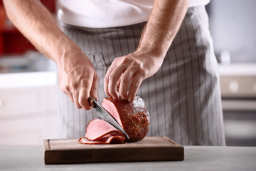 Obraz na płótnie Canvas Chef slicing yummy honey baked ham on wooden board