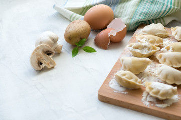 Process of cooking vareniki. Raw dumplings with potato and mushrooms. Concrete table. Side view. 