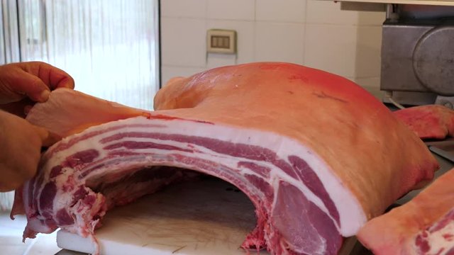 Butcher cutting pork meat on the table.